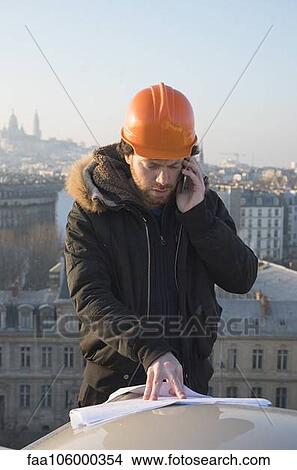 Construction supervisor talking on cell phone and looking at blueprints View Large Photo Image Picture - Construction supervisor talking on cell phone and looking at blueprints. Fotosearch