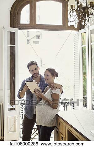 Couple at home looking at digital tablet together View Large Photo Image Stock Photography - Couple at home looking at digital tablet together. Fotosearch