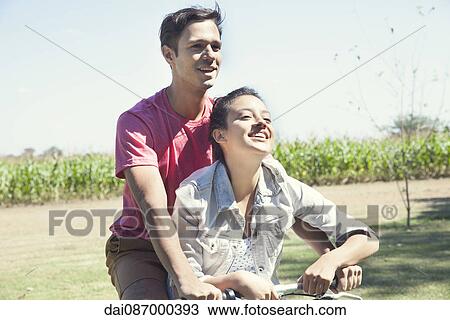 Stock Image - Couple riding bike together. Fotosearch