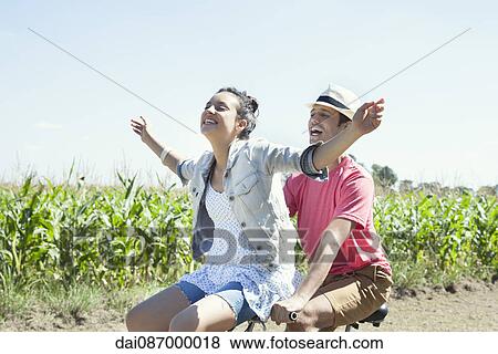 Couple riding bike together, woman with arms outstretched View Large Photo Image Stock Photo - Couple riding bike together, woman with arms outstretched. Fotosearch