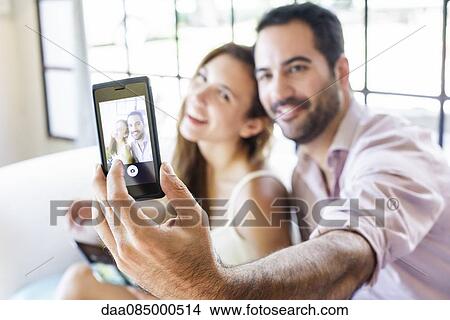 Picture - Couple taking selfie. Fotosearch