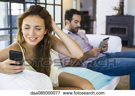 Couple using wireless devices at home View Large Photo Image Stock Photo - Couple using wireless devices at home. Fotosearch