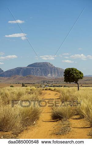 Stock Photo - Dirt road with Bishop's Hat Rock in the background, Madagascar. Fotosearch