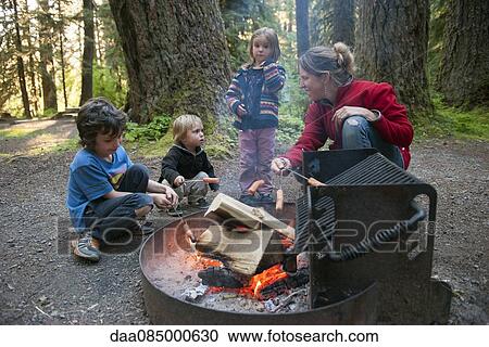 Family cooking hotdogs over campfire View Large Photo Image Stock Image - Family cooking hotdogs over campfire. Fotosearch