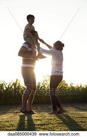 Stock Photo - Family spending time outdoors together, father carrying little boy on shoulders. Fotosearch