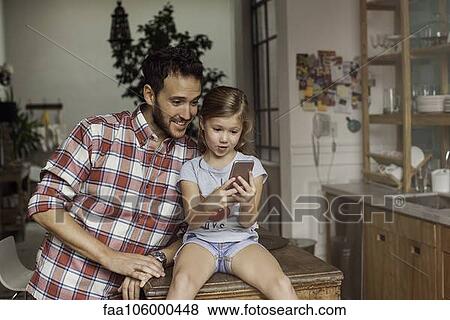 Father and daughter looking at smartphone together View Large Photo Image Stock Photo - Father and daughter looking at smartphone together. Fotosearch