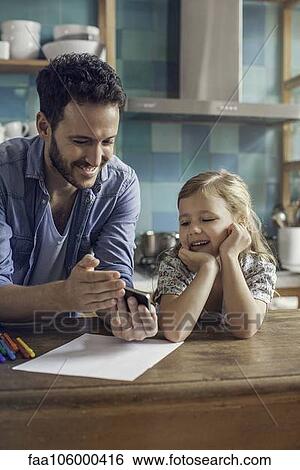 Father and daughter watch video streaming on smartphone together View Large Photo Image Stock Photograph - Father and daughter watch video streaming on smartphone together. Fotosearch