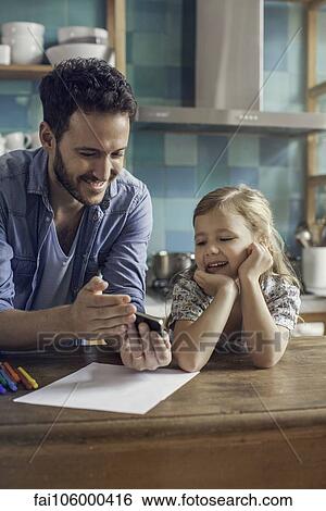 Father and daughter watch video streaming on smartphone together View Large Photo Image Stock Photograph - Father and daughter watch video streaming on smartphone together. Fotosearch