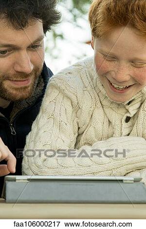 Father and son using digital tablet together View Large Photo Image Stock Photo - Father and son using digital tablet together. Fotosearch