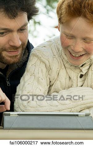 Stock Photo - Father and son using digital tablet together. Fotosearch
