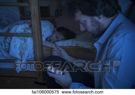 Stock Photography - Father checking smartphone while comforting sick daughter. Fotosearch