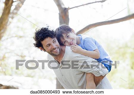 Stock Image - Father giving little boy piggyback ride. Fotosearch
