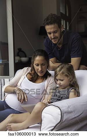 Father looking on as mother and daughter use digital tablet together View Large Photo Image Stock Image - Father looking on as mother and daughter use digital tablet together. Fotosearch