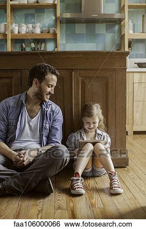Father looks on as daughter watches amusing video streaming on digital tablet View Large Photo Image Stock Photograph - Father looks on as daughter watches amusing video streaming on digital tablet. Fotosearch