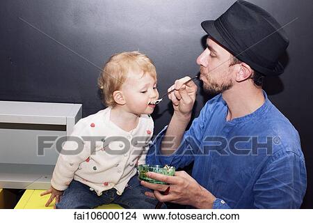 Father spoon feeding toddler View Large Photo Image Picture - Father spoon feeding toddler. Fotosearch