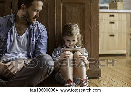 Father watching as daughter plays video game View Large Photo Image Picture - Father watching as daughter plays video game. Fotosearch