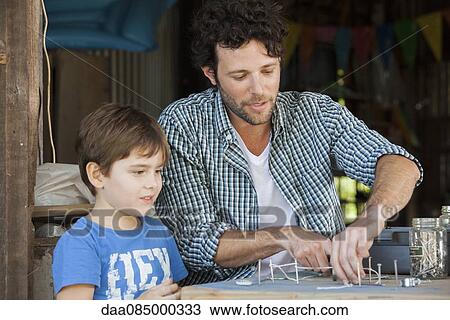 Father watching as young son creates art project with nails and string View Large Photo Image Stock Image - Father watching as young son creates art project with nails and string. Fotosearch