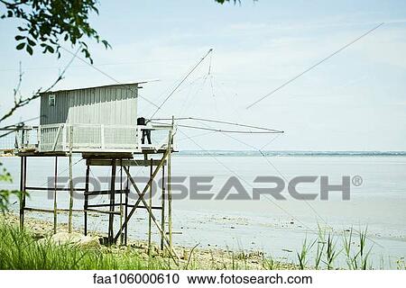 Stock Image - Fishing hut on stilts near water's edge. Fotosearch