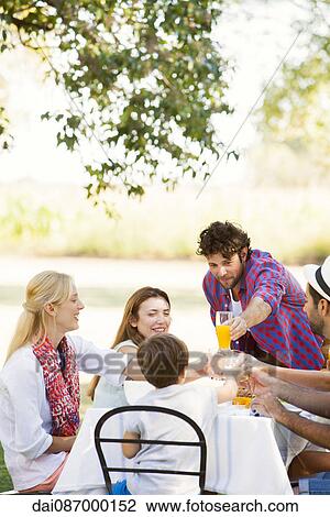 Friends clinking glasses while enjoying meal together outdoors View Large Photo Image Stock Image - Friends clinking glasses while enjoying meal together outdoors. Fotosearch