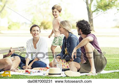 Friends enjoying picnic in park View Large Photo Image Stock Image - Friends enjoying picnic in park. Fotosearch