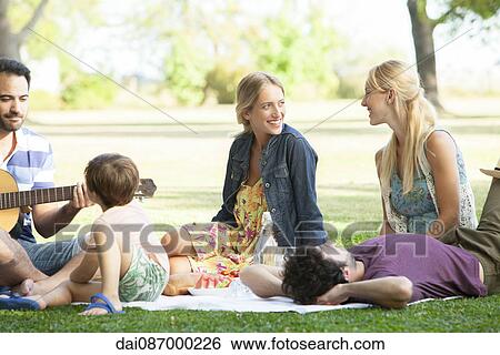 Friends enjoying picnic in park View Large Photo Image Stock Photograph - Friends enjoying picnic in park. Fotosearch