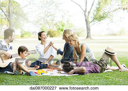 Friends having lighthearted moment while picnicking in park View Large Photo Image Stock Photo - Friends having lighthearted moment while picnicking in park. Fotosearch