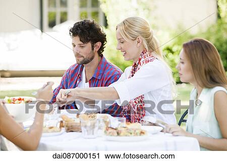 Friends having meal together outdoors View Large Photo Image Stock Image - Friends having meal together outdoors. Fotosearch