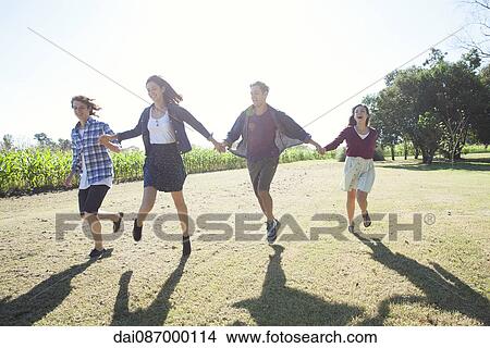 Friends holding hands running through field View Large Photo Image Picture - Friends holding hands running through field. Fotosearch