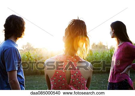 Stock Image - Friends watching sunset together. Fotosearch