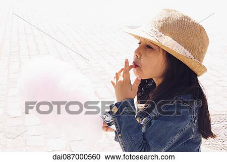 Stock Image - Girl eating cotton candy. Fotosearch