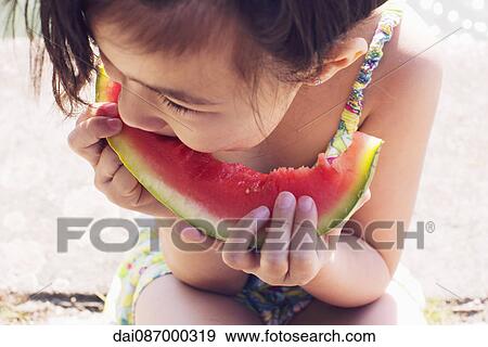 Stock Photo - Girl eating watermelon, close-up. Fotosearch
