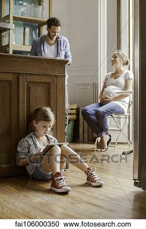 Girl sitting alone playing video game while parents chat View Large Photo Image Stock Image - Girl sitting alone playing video game while parents chat. Fotosearch