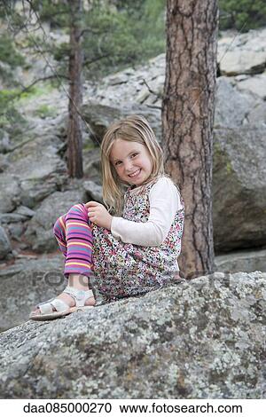 Girl sitting on rock, smiling cheerfully View Large Photo Image Stock Image - Girl sitting on rock, smiling cheerfully. Fotosearch