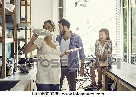 Stock Photo - Girl watching as parents prepare family meal. Fotosearch