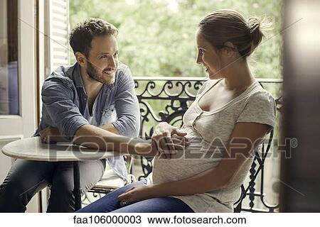 Stock Image - Husband resting hand on wife's pregnant stomach. Fotosearch
