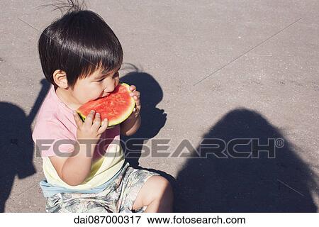 Stock Photo - Little boy eating watermelon outdoors. Fotosearch