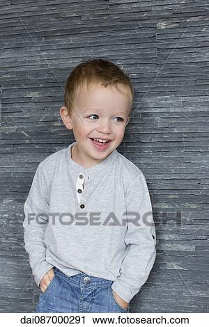 Little boy leaning against wall with hands in pockets, smiling cheerfully View Large Photo Image Stock Image - Little boy leaning against wall with hands in pockets, smiling cheerfully. Fotosearch