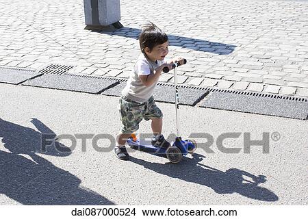 Little boy riding push scooter View Large Photo Image Picture - Little boy riding push scooter. Fotosearch