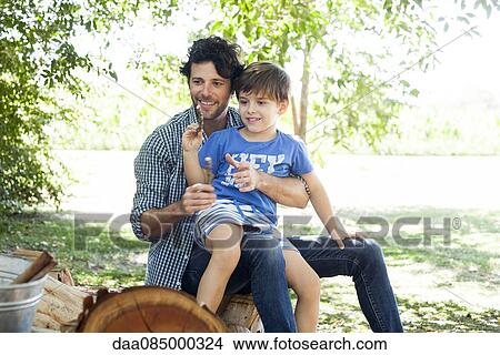 Picture - Little boy with father tossing sticks into bucket. Fotosearch
