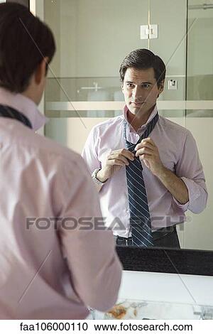 Man adjusting necktie in bathroom mirror View Large Photo Image Stock Image - Man adjusting necktie in bathroom mirror. Fotosearch