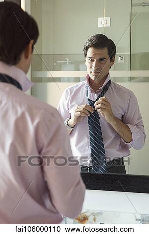 Man adjusting necktie in bathroom mirror View Large Photo Image Stock Image - Man adjusting necktie in bathroom mirror. Fotosearch