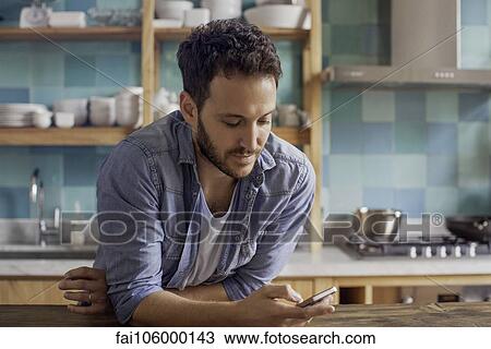 Man at home in kitchen text messaging View Large Photo Image Stock Image - Man at home in kitchen text messaging. Fotosearch