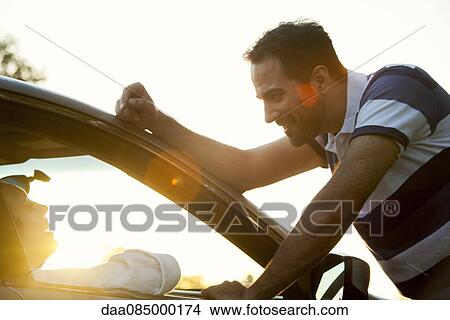 Man chatting with woman sitting in car passenger seat View Large Photo Image Picture - Man chatting with woman sitting in car passenger seat. Fotosearch