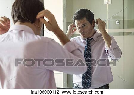 Man fixing his hair in bathroom mirror View Large Photo Image Stock Image - Man fixing his hair in bathroom mirror. Fotosearch