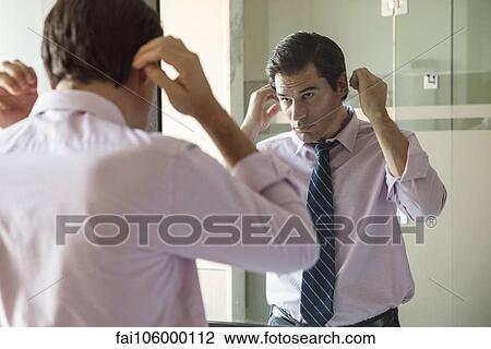 Man fixing his hair in bathroom mirror View Large Photo Image Stock Image - Man fixing his hair in bathroom mirror. Fotosearch