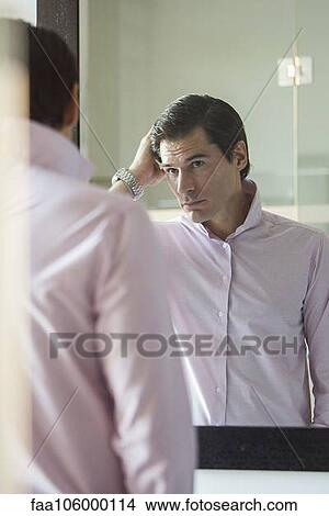 Man fixing his hair in mirror View Large Photo Image Picture - Man fixing his hair in mirror. Fotosearch