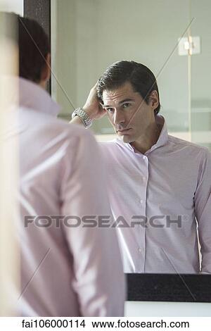 Man fixing his hair in mirror View Large Photo Image Picture - Man fixing his hair in mirror. Fotosearch