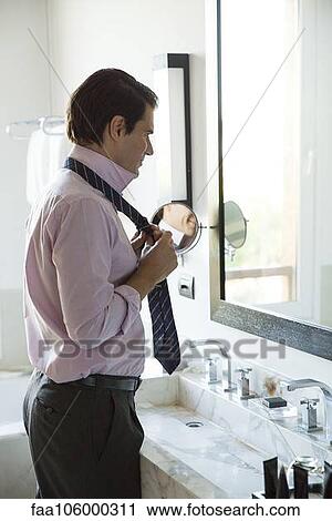 Man getting dressed, adjusting tie in mirror View Large Photo Image Stock Image - Man getting dressed, adjusting tie in mirror. Fotosearch