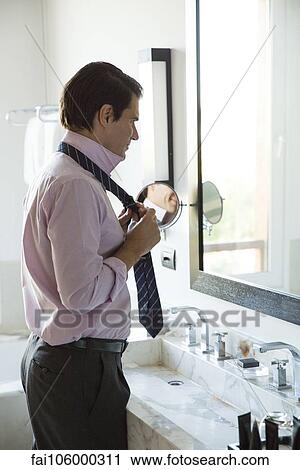 Man getting dressed, adjusting tie in mirror View Large Photo Image Stock Image - Man getting dressed, adjusting tie in mirror. Fotosearch