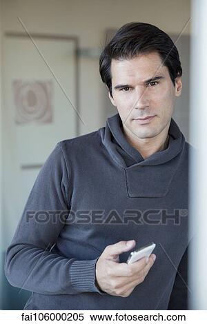Stock Photography - Man holding cell phone, portrait. Fotosearch